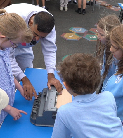 Instructor teaching a group of primary school children how to use braille